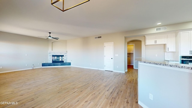 unfurnished living room featuring ceiling fan, a fireplace, and light hardwood / wood-style floors