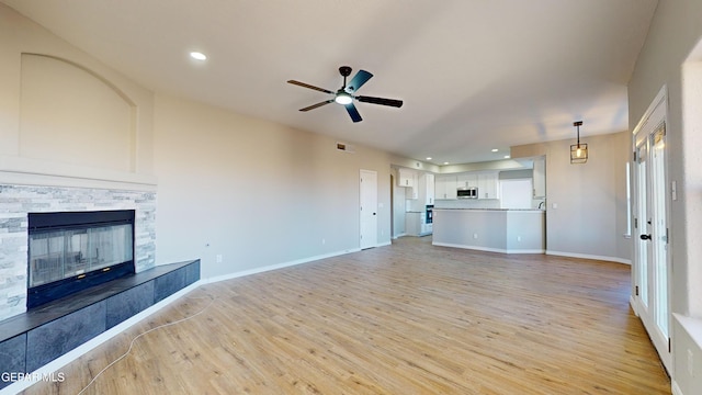 unfurnished living room featuring a fireplace, light hardwood / wood-style flooring, and ceiling fan