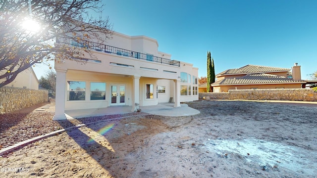 back of property featuring a patio area, french doors, and a balcony