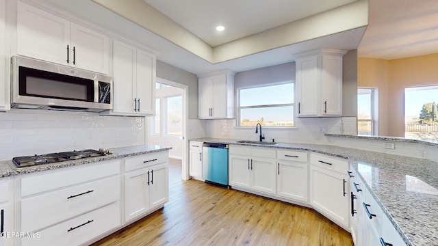 kitchen featuring light stone countertops, sink, white cabinets, and appliances with stainless steel finishes