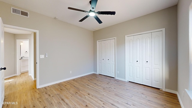 unfurnished bedroom with ceiling fan, light hardwood / wood-style flooring, and multiple closets