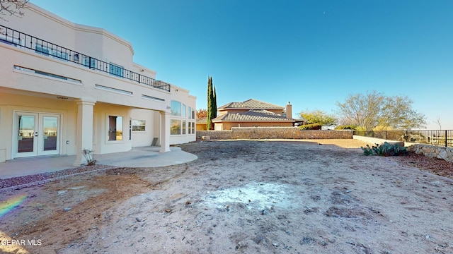 view of yard featuring french doors, a patio, and a balcony