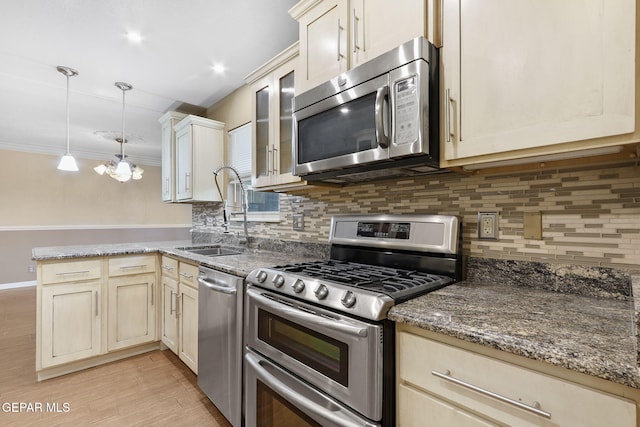 kitchen featuring appliances with stainless steel finishes, backsplash, sink, decorative light fixtures, and dark stone countertops