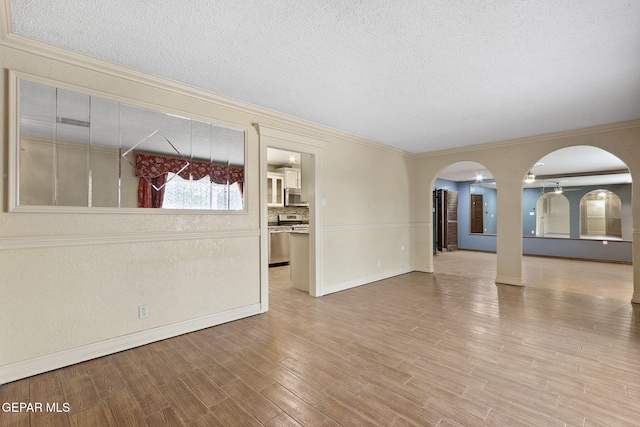 spare room featuring hardwood / wood-style floors, a textured ceiling, and ornamental molding