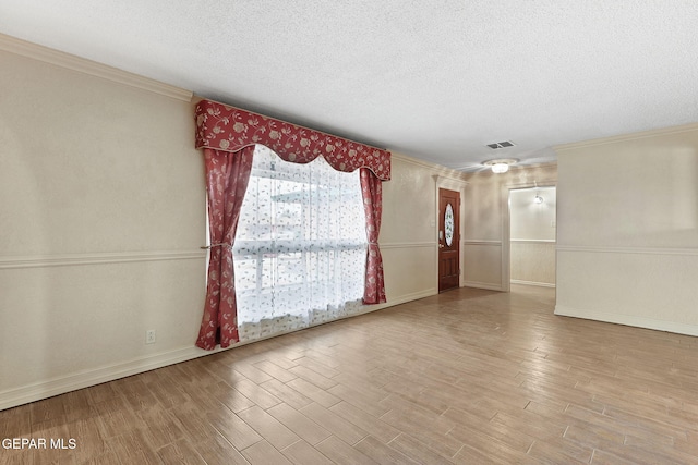 unfurnished room with crown molding, light hardwood / wood-style floors, and a textured ceiling