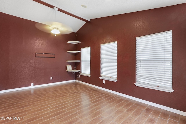 spare room featuring vaulted ceiling with beams, ceiling fan, and wood-type flooring