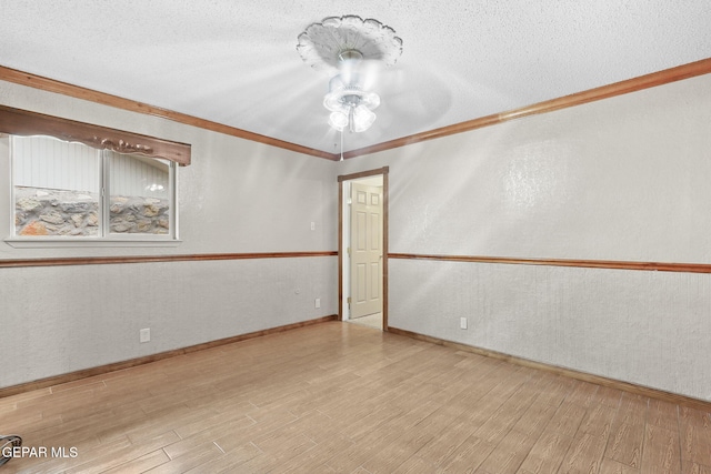 empty room with a textured ceiling, light hardwood / wood-style flooring, and crown molding