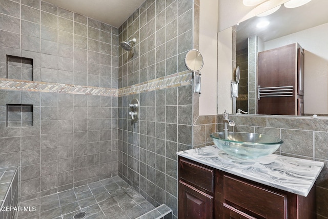 bathroom with vanity, tiled shower, tile walls, and tasteful backsplash