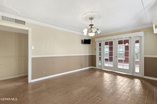 empty room with french doors, wood-type flooring, a textured ceiling, and a notable chandelier