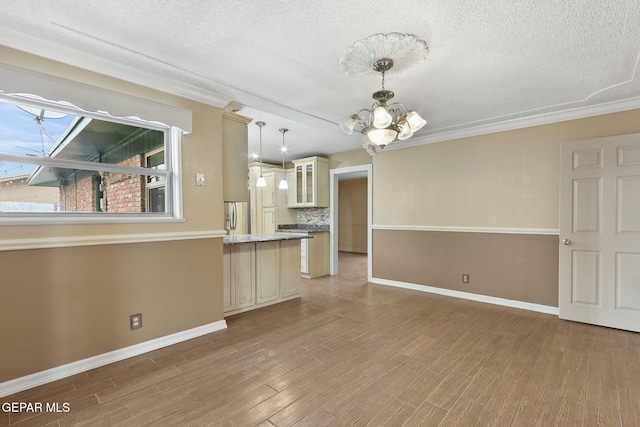 interior space with a textured ceiling, light hardwood / wood-style flooring, a notable chandelier, and crown molding