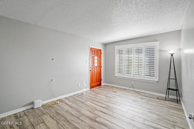 spare room featuring light hardwood / wood-style floors and a textured ceiling