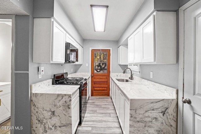 kitchen with white cabinets, sink, light stone countertops, and black appliances