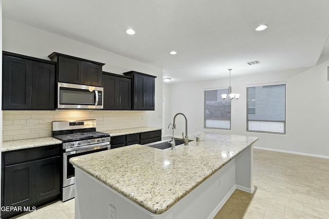 kitchen featuring a center island with sink, hanging light fixtures, sink, and appliances with stainless steel finishes