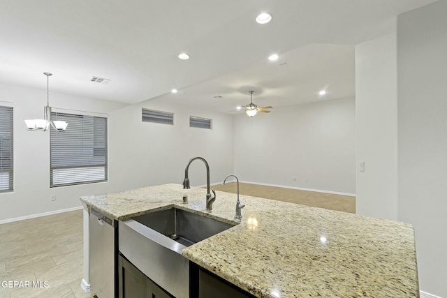 kitchen featuring light stone countertops, dishwasher, sink, pendant lighting, and ceiling fan with notable chandelier