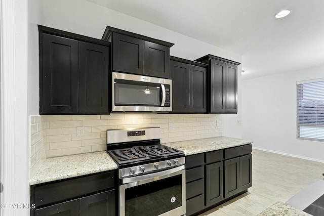 kitchen with light wood-type flooring, backsplash, stainless steel appliances, and light stone counters