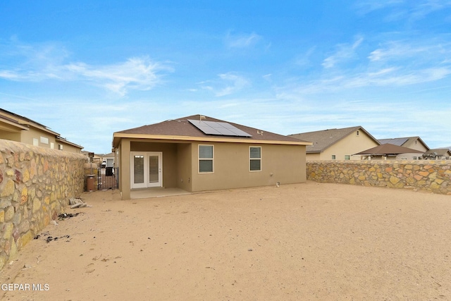 back of property with solar panels and french doors