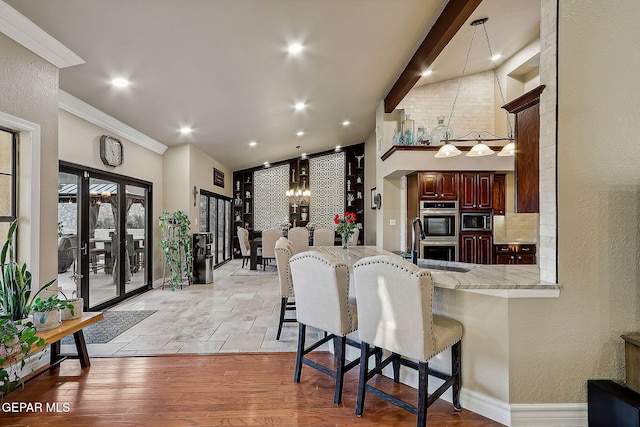 kitchen with light hardwood / wood-style floors, pendant lighting, kitchen peninsula, appliances with stainless steel finishes, and a kitchen breakfast bar