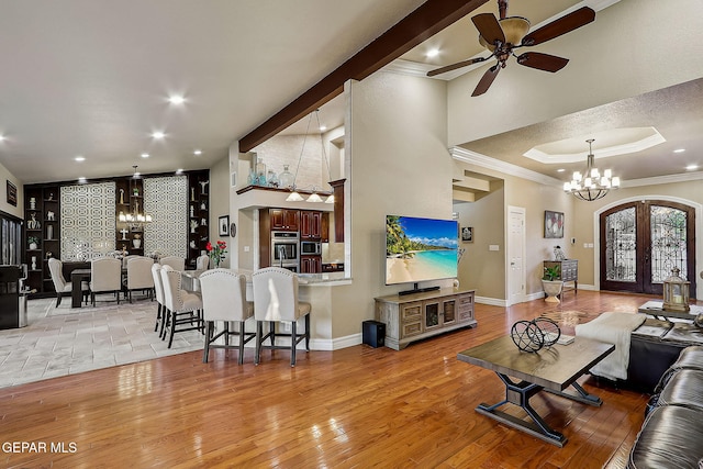 living room with ceiling fan with notable chandelier, light hardwood / wood-style floors, crown molding, and french doors