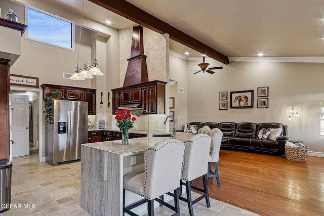 kitchen featuring sink, stainless steel fridge with ice dispenser, kitchen peninsula, a breakfast bar, and beam ceiling