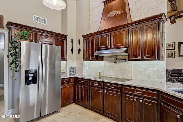 kitchen featuring a high ceiling, black electric stovetop, backsplash, stainless steel fridge with ice dispenser, and light stone counters