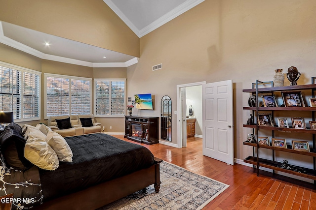 bedroom featuring ensuite bathroom, a fireplace, wood-type flooring, high vaulted ceiling, and ornamental molding