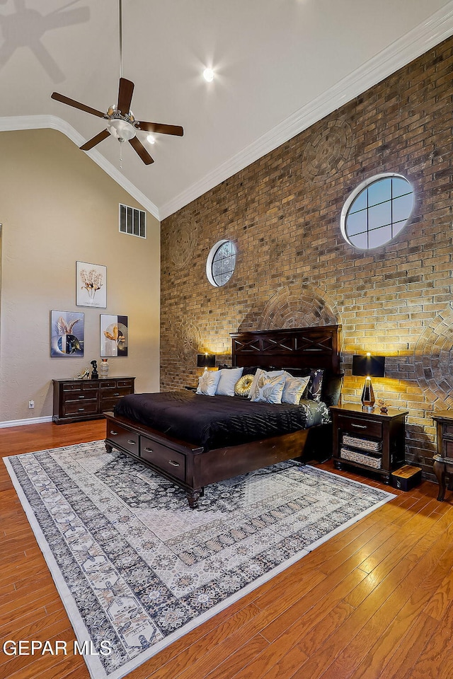 bedroom with ceiling fan, brick wall, crown molding, and vaulted ceiling