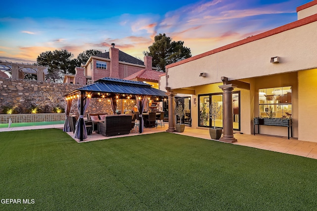 back house at dusk featuring a lawn, a gazebo, an outdoor living space, and a patio