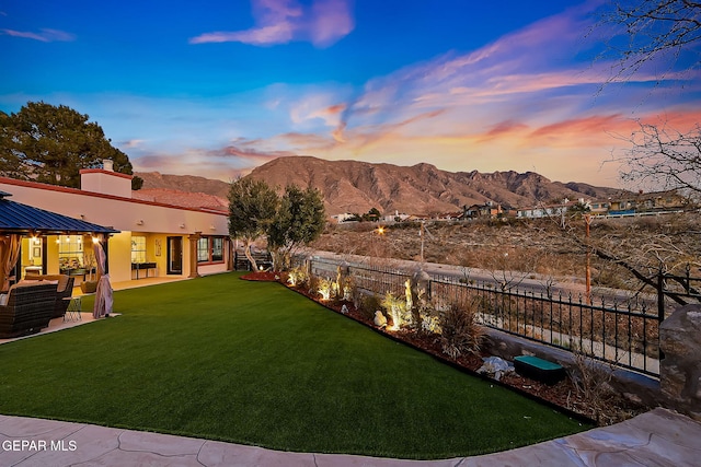 yard at dusk featuring a mountain view and a patio area