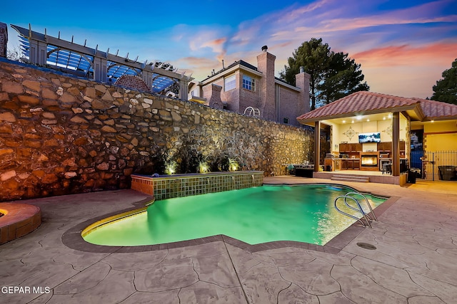 pool at dusk with an outdoor kitchen and a patio area