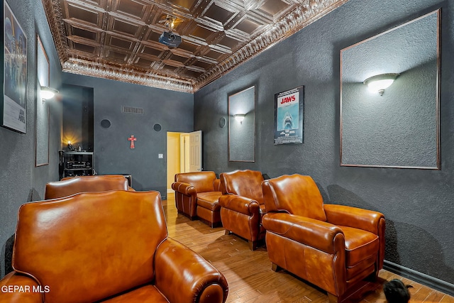 cinema room with hardwood / wood-style floors, crown molding, and coffered ceiling