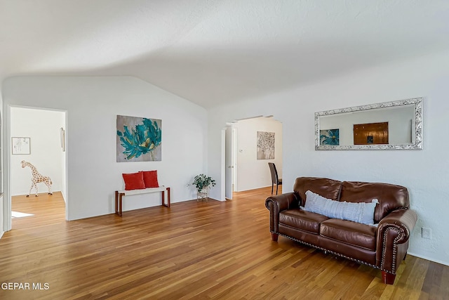 sitting room with hardwood / wood-style flooring, decorative columns, and vaulted ceiling