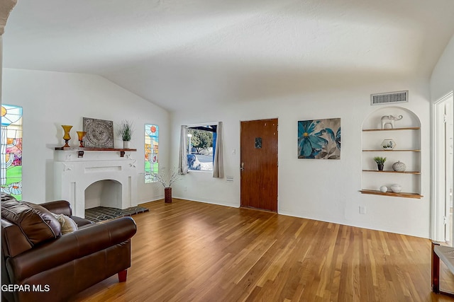 living room featuring built in shelves, lofted ceiling, and wood-type flooring