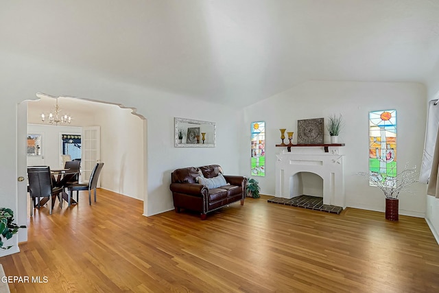 living room featuring hardwood / wood-style floors, lofted ceiling, and an inviting chandelier