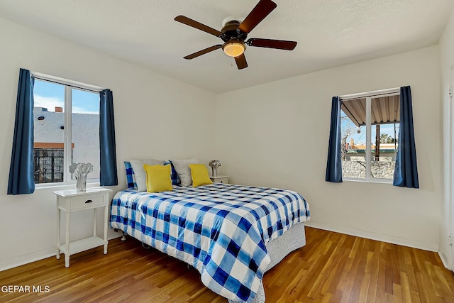 bedroom with multiple windows, ceiling fan, and hardwood / wood-style flooring