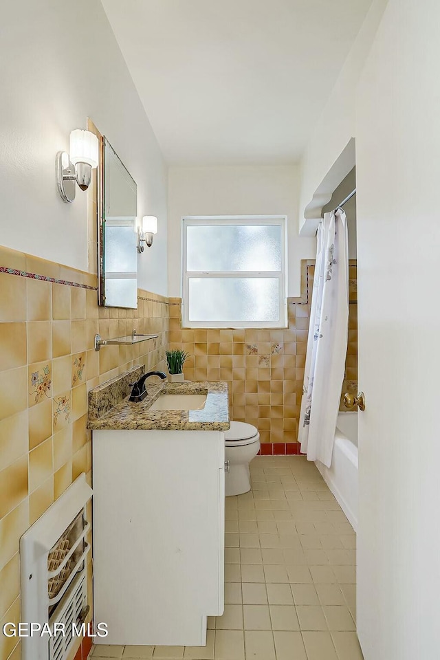 full bathroom with shower / bathtub combination with curtain, tile patterned flooring, toilet, vanity, and tile walls