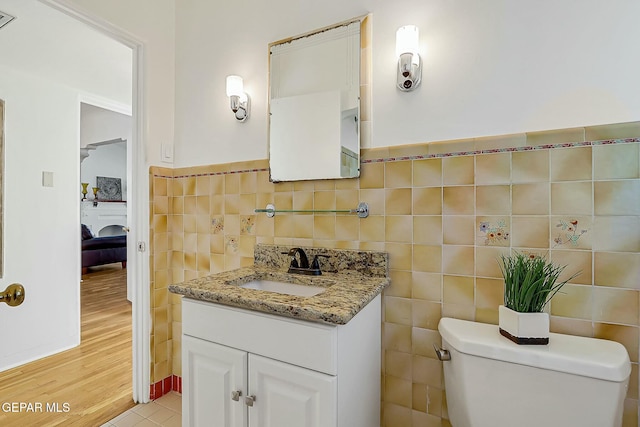 bathroom with tile patterned floors, vanity, toilet, and tile walls