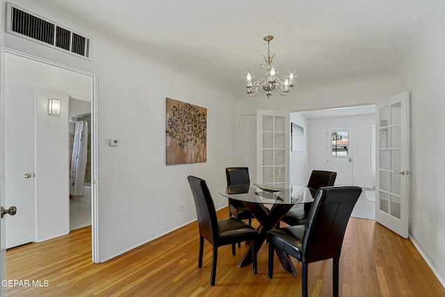 dining room with french doors, light hardwood / wood-style floors, and a notable chandelier