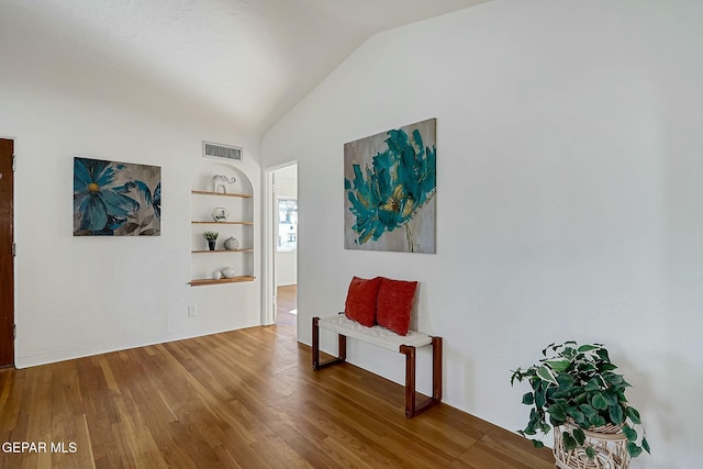 interior space featuring built in shelves, hardwood / wood-style flooring, and vaulted ceiling