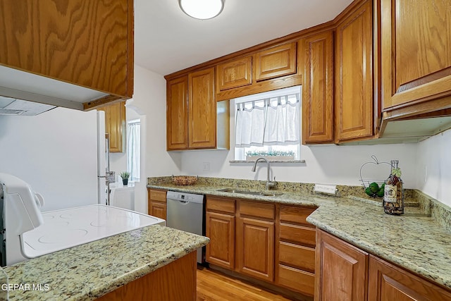 kitchen featuring light stone countertops, white refrigerator, stainless steel dishwasher, and sink