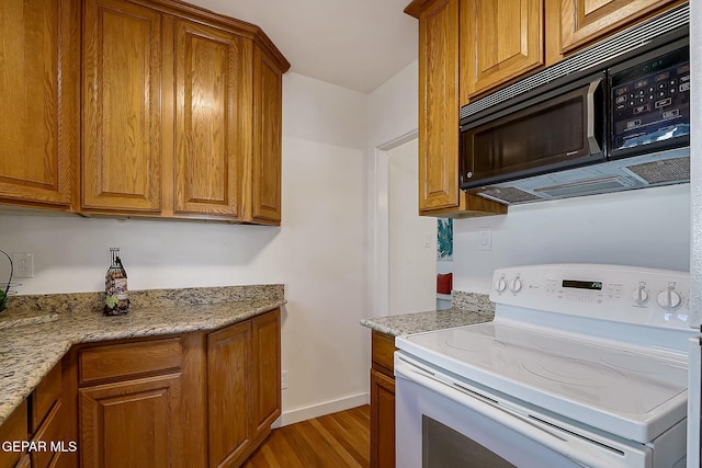 kitchen with white electric range oven, wood-type flooring, and light stone countertops