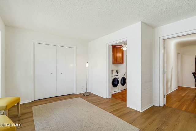 laundry room featuring cabinets, light hardwood / wood-style flooring, ceiling fan, independent washer and dryer, and a textured ceiling