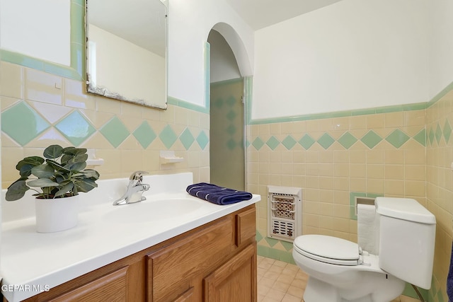 bathroom with vanity, tile patterned flooring, toilet, tile walls, and heating unit