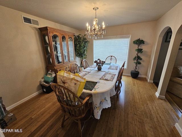 dining space with dark hardwood / wood-style flooring and a notable chandelier