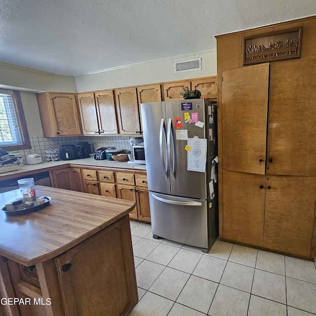 kitchen featuring stainless steel fridge, a textured ceiling, tasteful backsplash, and light tile patterned flooring