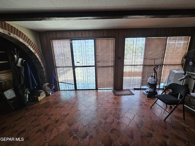 interior space with beamed ceiling, plenty of natural light, and wood walls