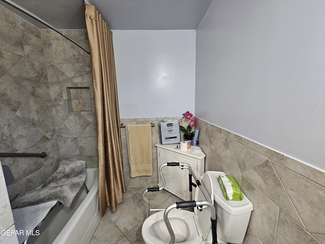 bathroom with tile patterned floors, shower / bath combo with shower curtain, tile walls, and toilet