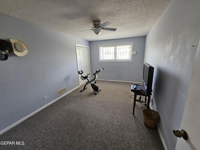 exercise room featuring carpet, ceiling fan, and a textured ceiling