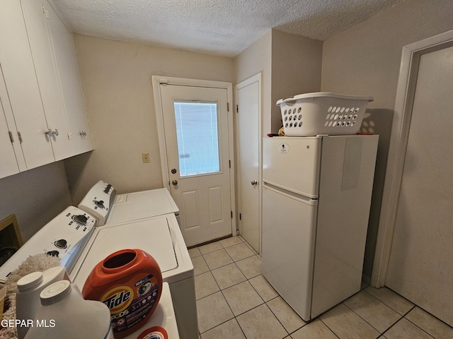 laundry area featuring light tile patterned flooring, cabinets, a textured ceiling, and independent washer and dryer