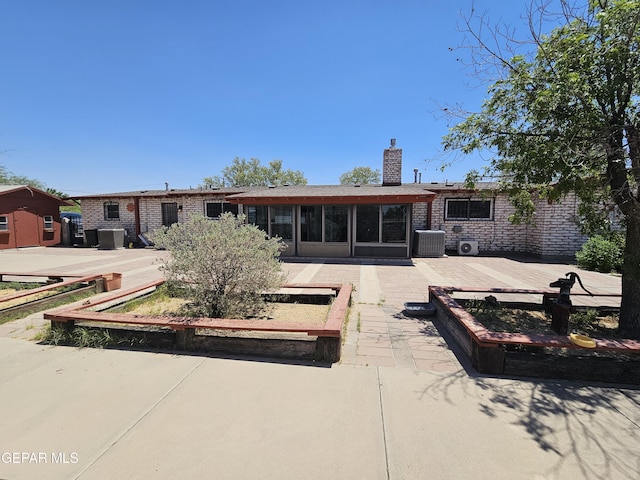 rear view of property featuring a sunroom, central air condition unit, and a patio