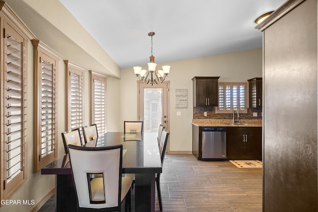 dining area featuring sink, lofted ceiling, and a notable chandelier